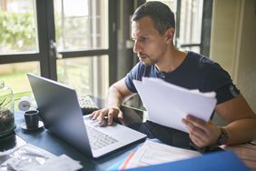 Man preparing his taxes on laptop in a home office.