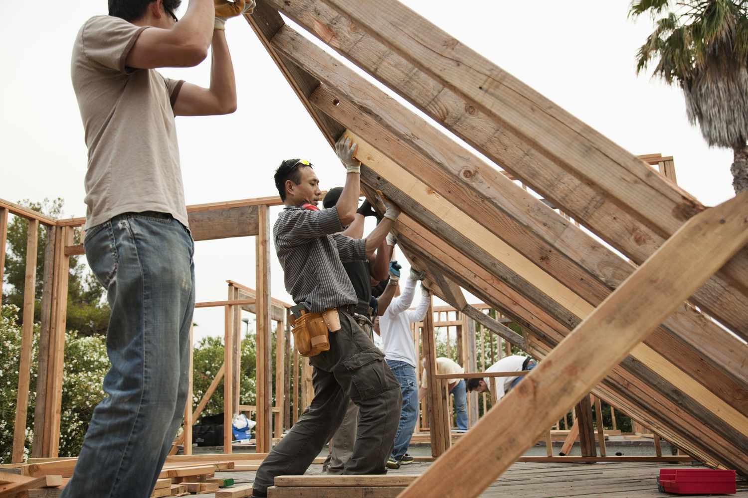 Construction workers lift a house frame.