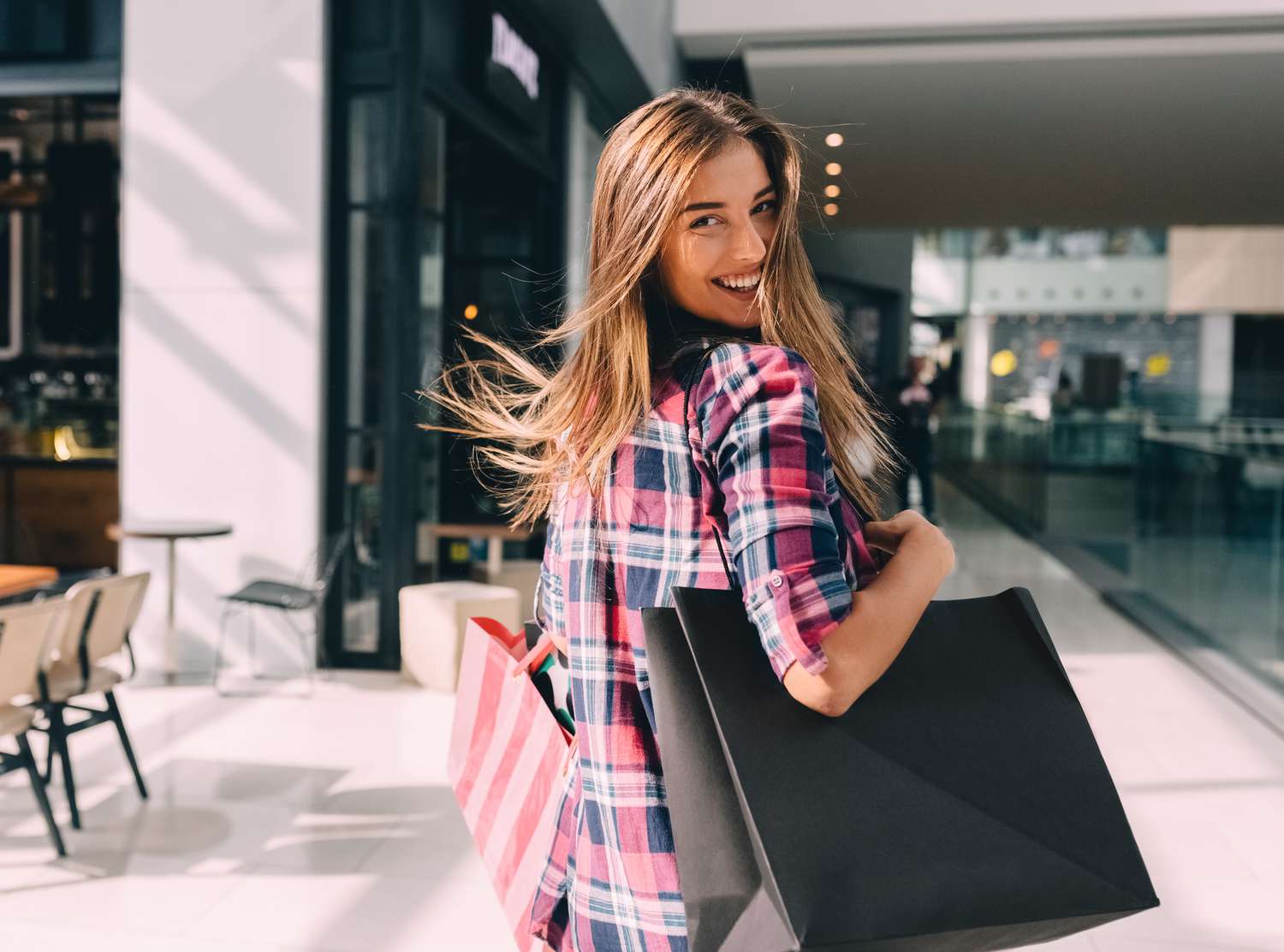 Happy woman with multiple shopping bags as she looks over her shoulder.