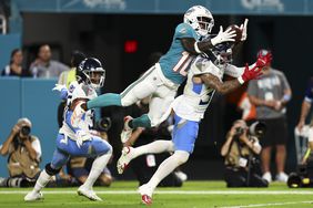 Miami Dolphins wide receiver Tyreek Hill jumps to catch a football over the head of Amani Hooker of the Tennessee Titans.