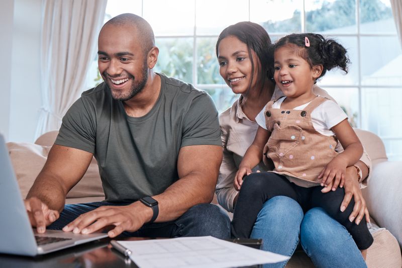 A couple with child looking for free business checking account on laptop.