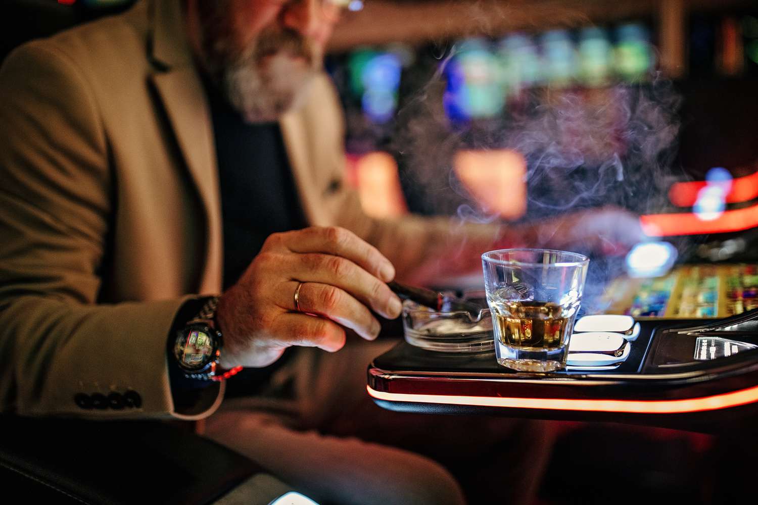 Person playing a casino game smokes a cigar and has an alcoholic drink