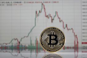 In this photo illustration, a visual representation of the digital Cryptocurrency, Bitcoin is displayed in front of the Bitcoin course's graph of Coinbase cryptocurrency exchange website on February 6, 2018.