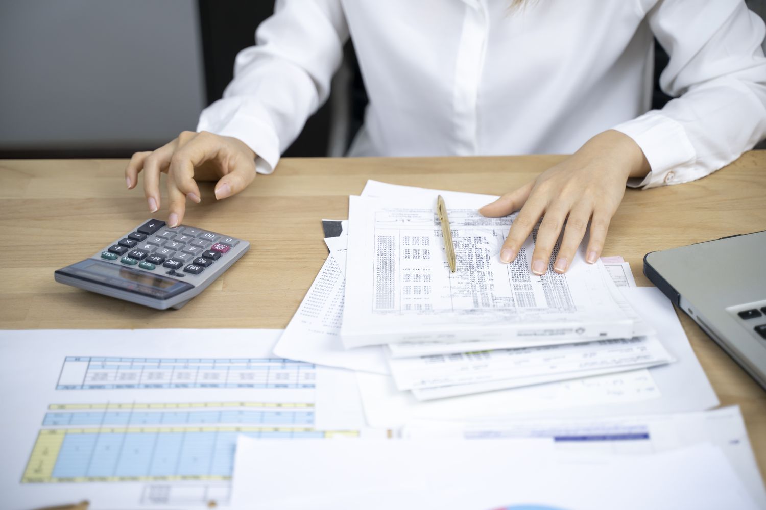 A person uses a calculater to add figures shown on a retirement plan statement.