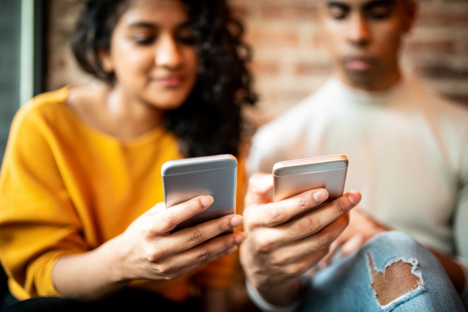 Two friends looking at their cellphones. 
