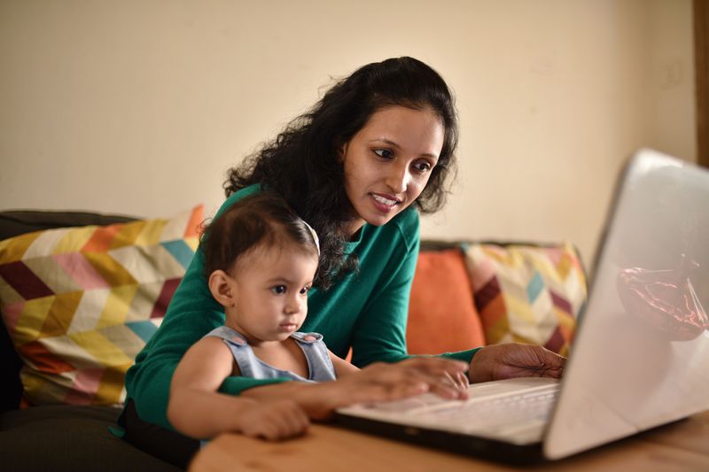 Woman shopping online with her toddler baby in the lap.