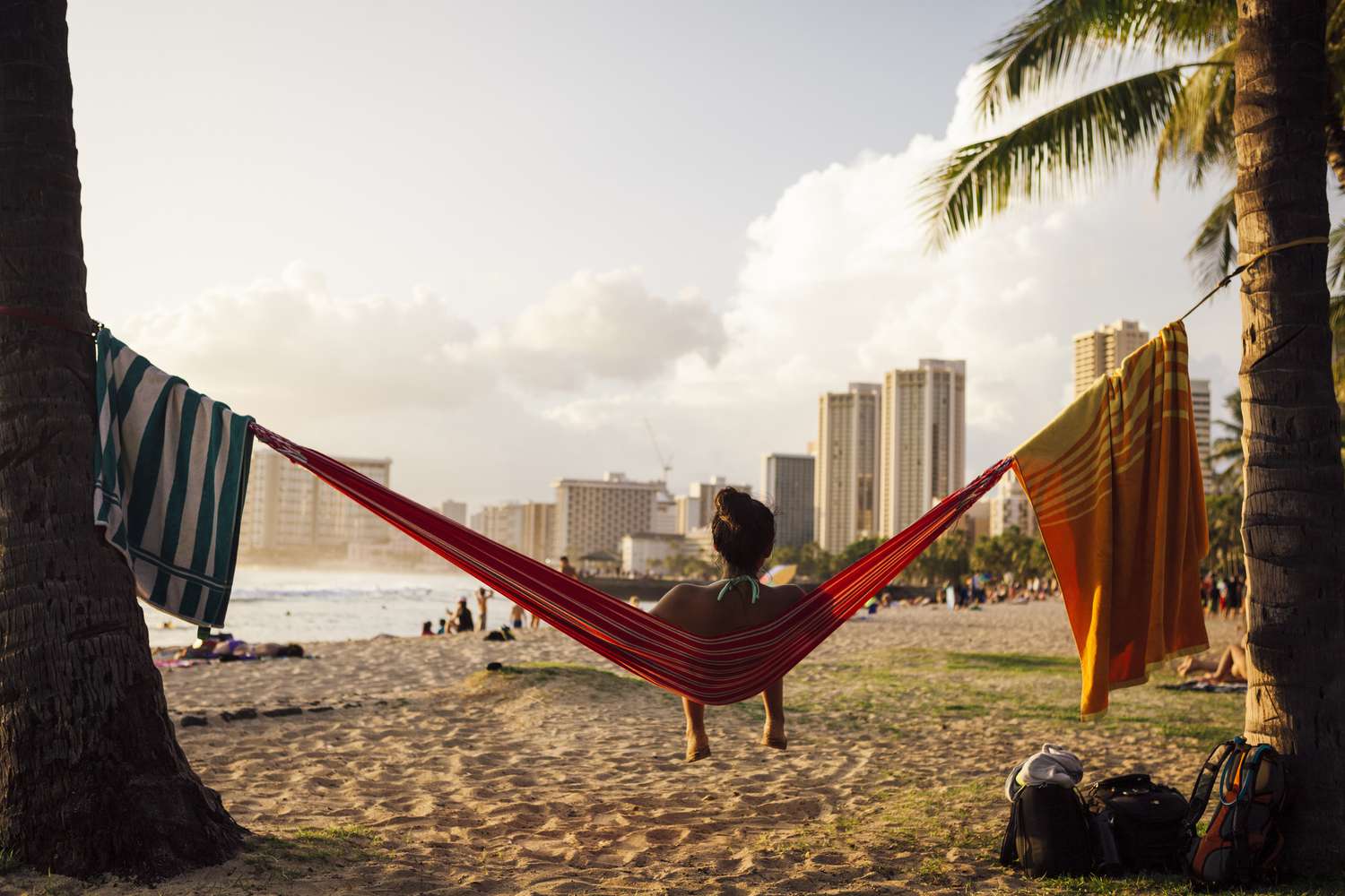 An adult in a hammock on Waikiki Beach, Hawaii, as the sun begins to set