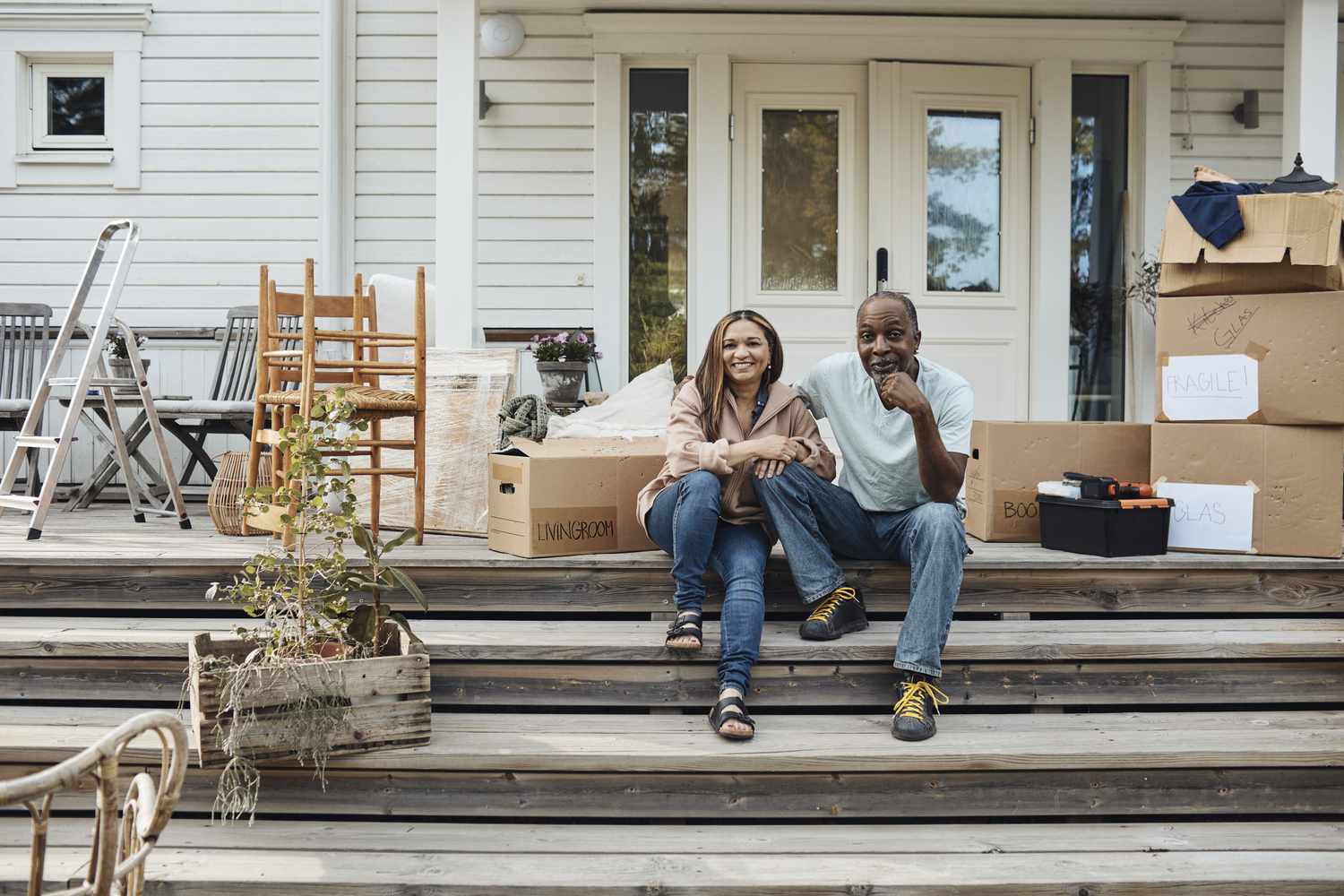 Man and woman sitting on steps outside of a house with moving boxes next to them