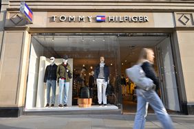 People walk past a Tommy Hilfiger luxury fashion label store in London