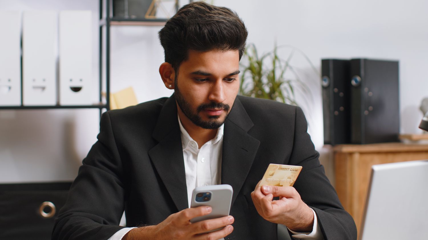 Business man making online payment with business credit card and smartphone at office
