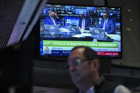 A trader works on the floor of the New York Stock Exchange in front of a screen showing stock market news