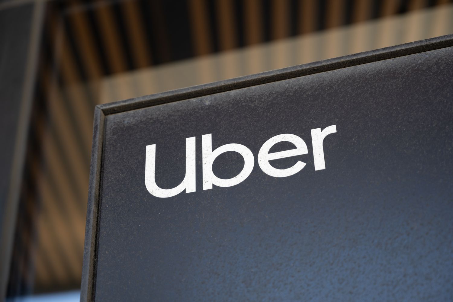 The Uber logo on a black sign in front of an office building window