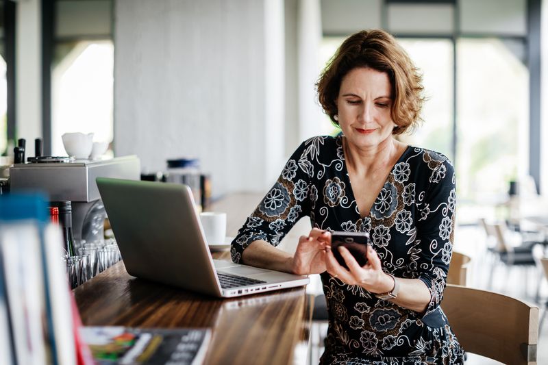 Stylish older woman at laptop with mobile phone