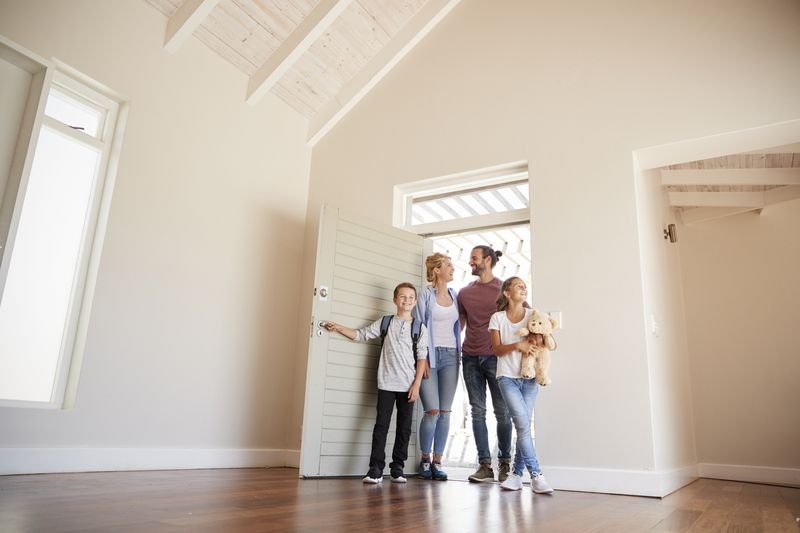 Family opening door and walking in empty lounge of an open house.