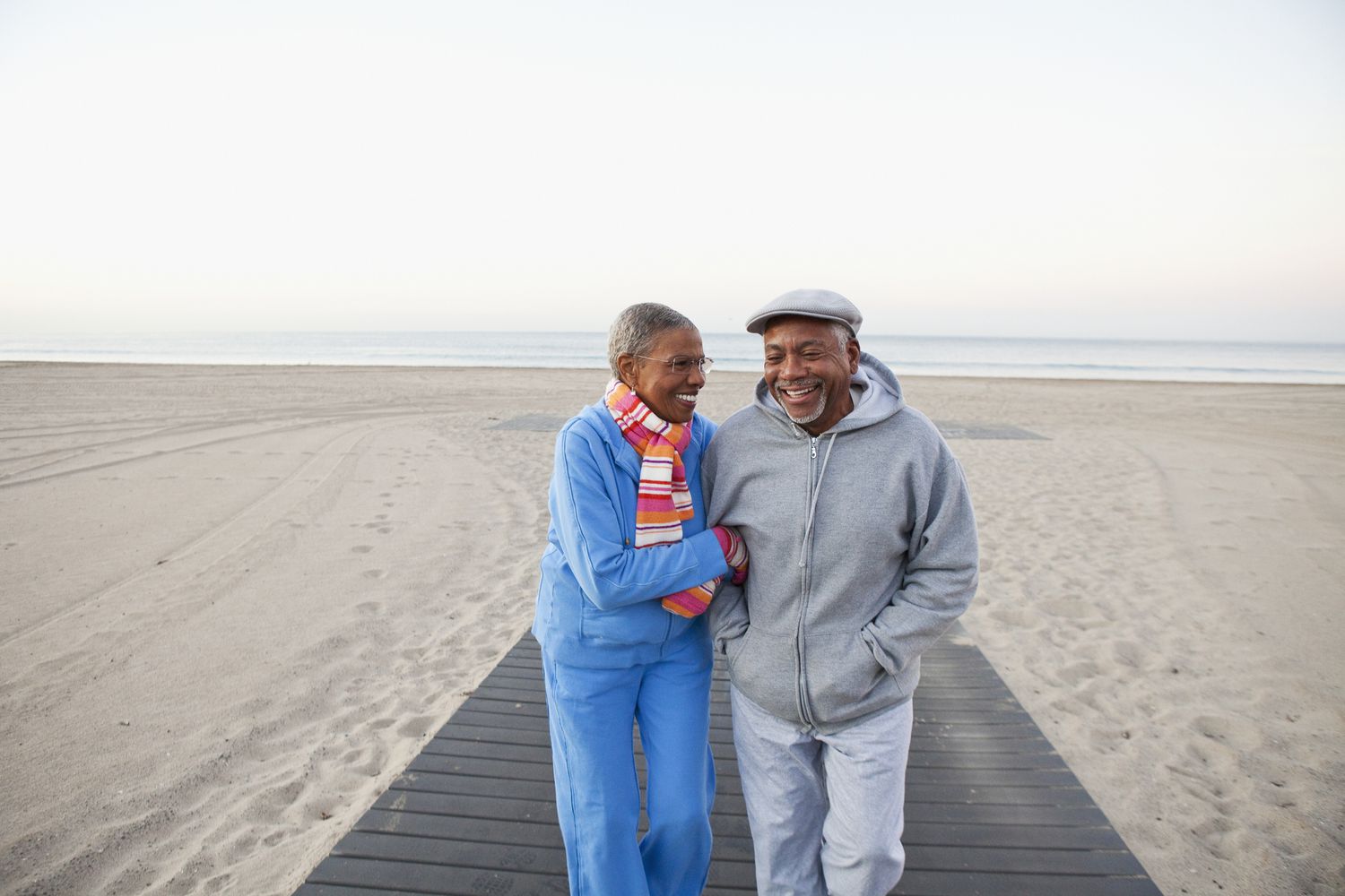 Senior couple walking together on a beach arm in arm.