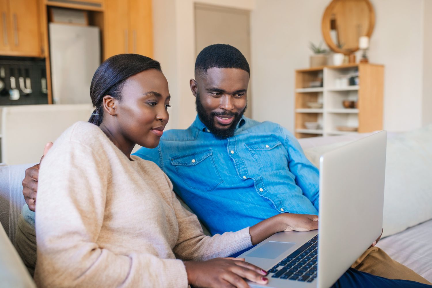 Young couple sitting on their sofa and looking at mortgage rates on a laptop