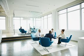 Business people sitting in an open plan office space engaging with each other. 