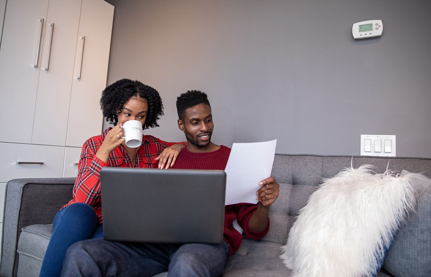 Young black couple looking at ways to lower their mortgage payment with laptop and paper