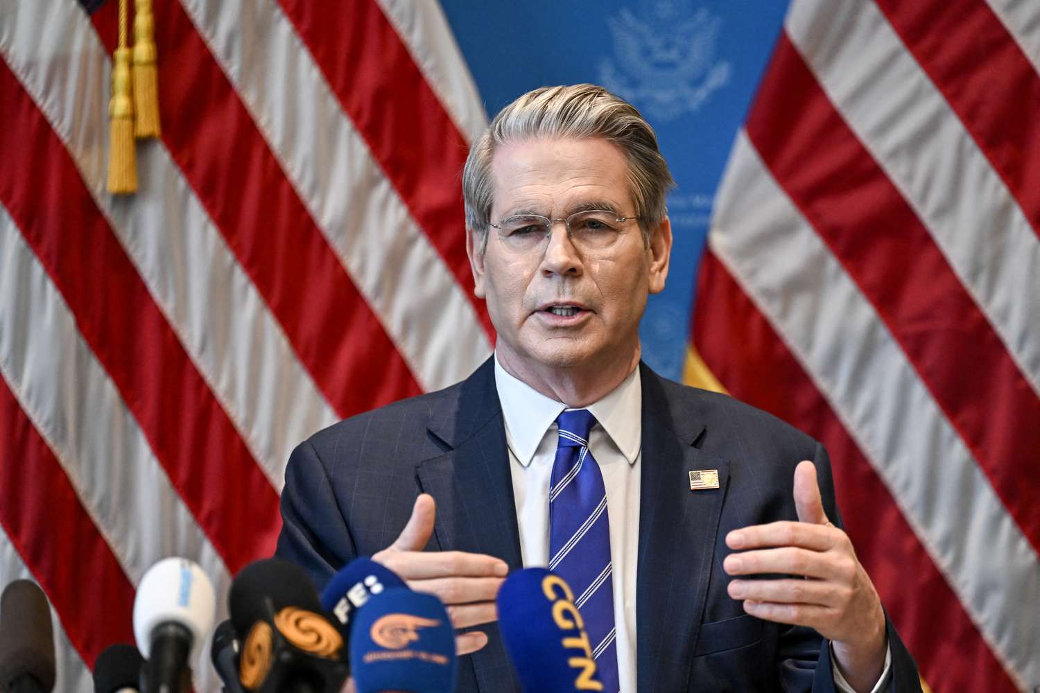 Treasury Secretary Scott Bessent speaks in front of two American flags.