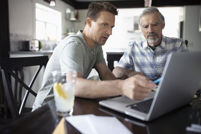 Son helping father using laptop