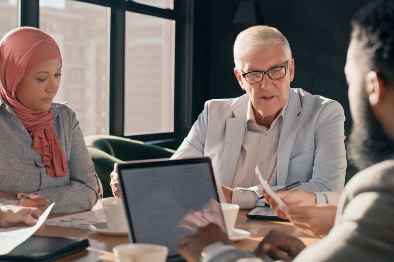 A investing couple talk to a financial advisor and compare potential funds by looking at the performance of the fund manager.