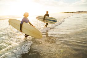 Older adults surfing at sunset