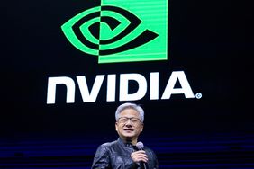 Nvidia CEO Jensen Huang speaks on a stage, with an Nvidia logo on a screen behind him.
