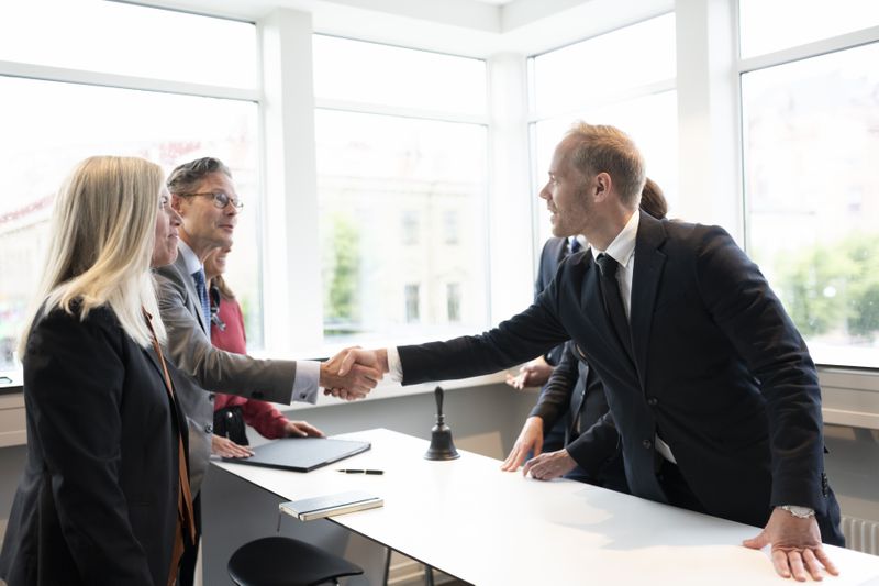 Institutional investors shake hands across a meeting table after the success of agreeing on a spot secondary trade.