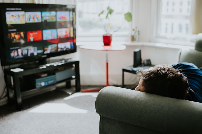 Man rests on the couch and considers what to stream.