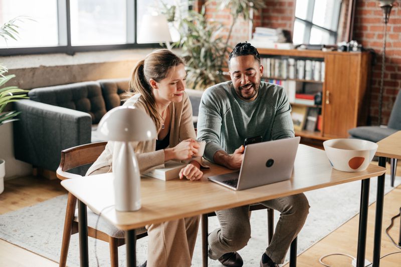 Two people looking at a laptop to check investments.