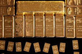 Gold bars are seen on a black table.
