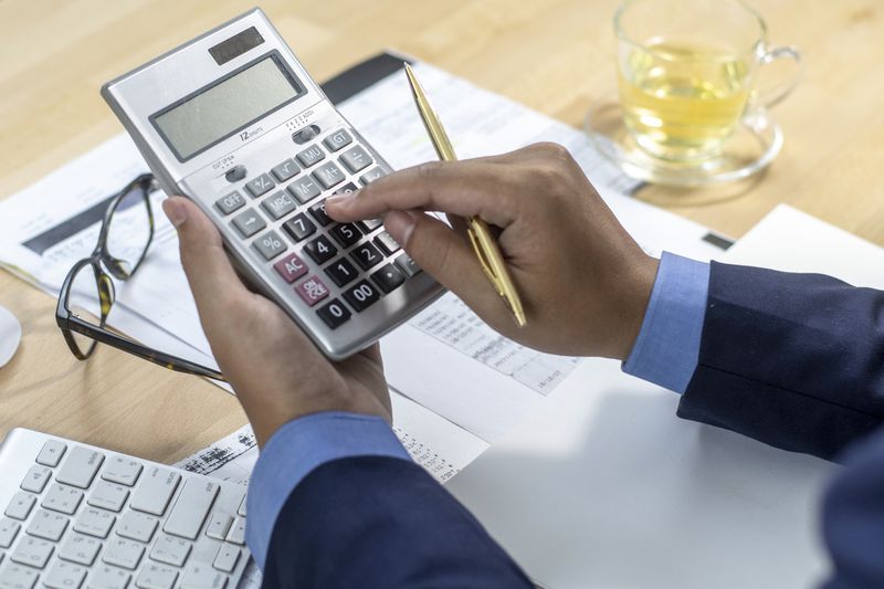 An Accountant working on a calculator while sitting at a desk.