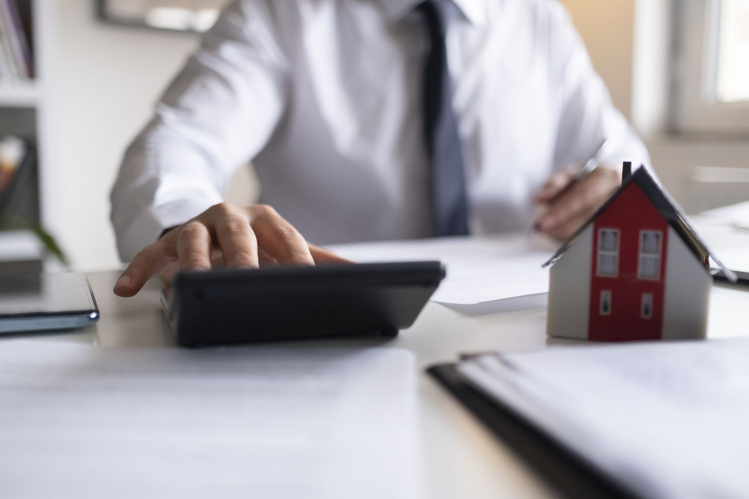 A real estate professional using calculator with computer laptop, budget and loan paper in office.