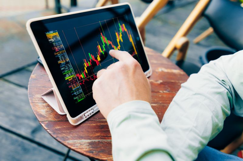 A trader uses a pad at a cafe table to check stock market data.