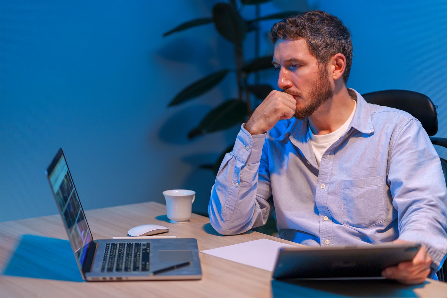 An options trader sits at desk looking at laptop and considering a synthetic call option strategy.