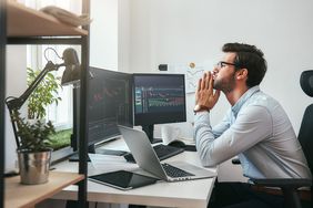 A concerned investor sitting at a desk monitoring market trading on computer screen