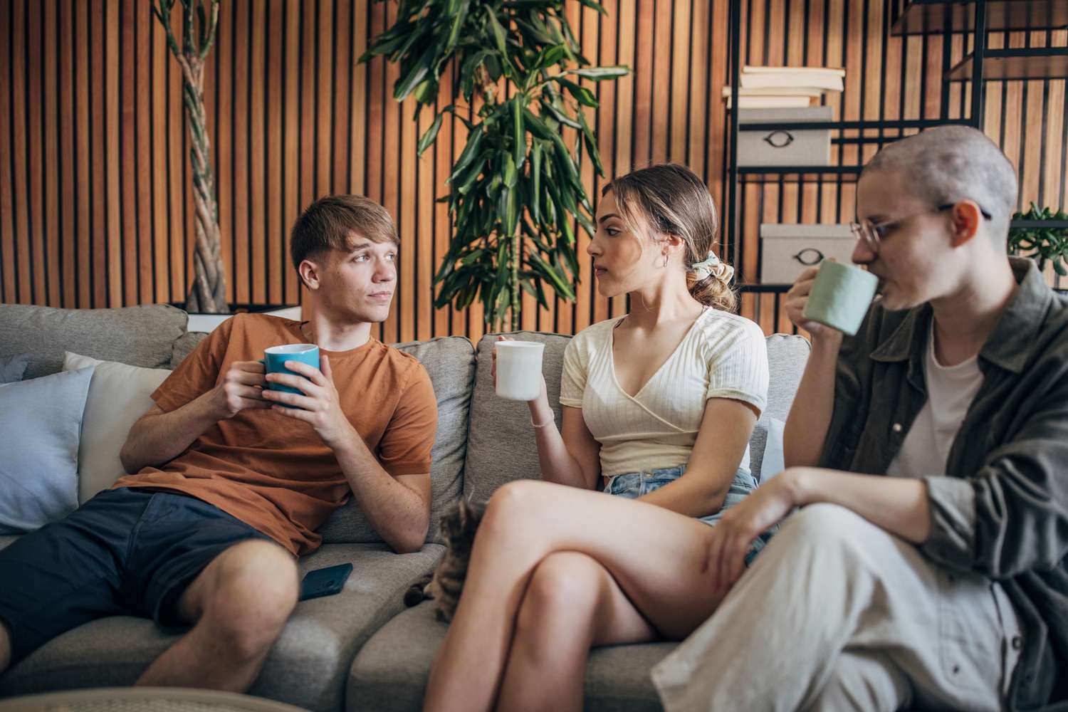 A group of friends sitting at home drinking coffee and having a financial intervention for one person from the group.
