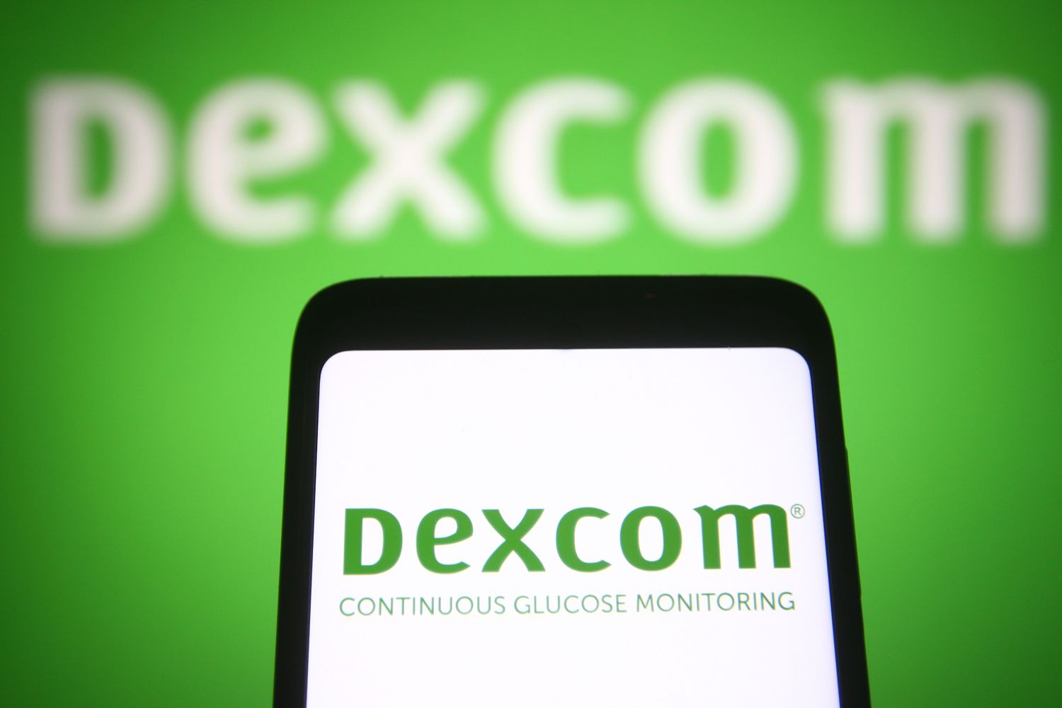 Dexcom logo on a smartphone screen and in background