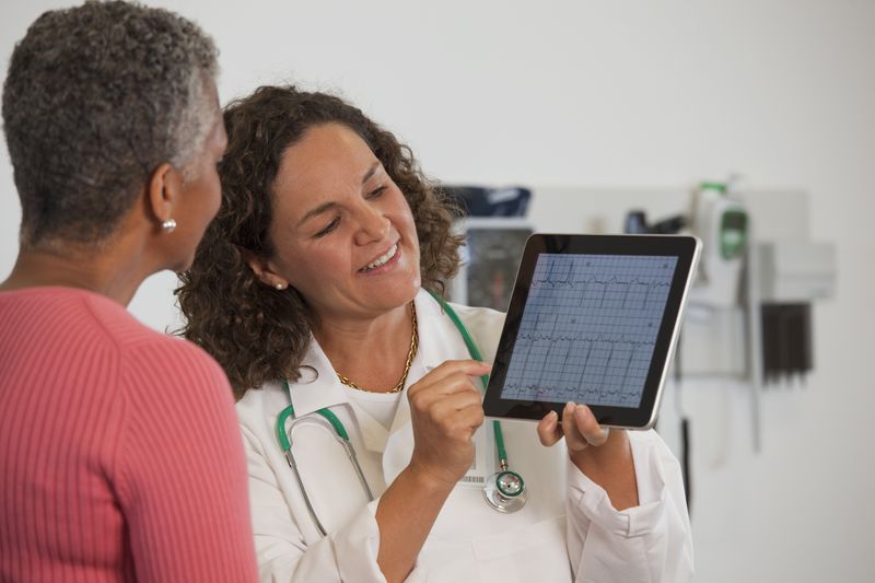Doctor showing a patient a tablet with EKG results.