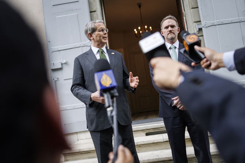 Scott Bessent and Jamieson Greer stand in front of the doorway at the residence of the permanent Swiss ambassador to the United Nations. Microphones are pointed toward them as they address reporters.