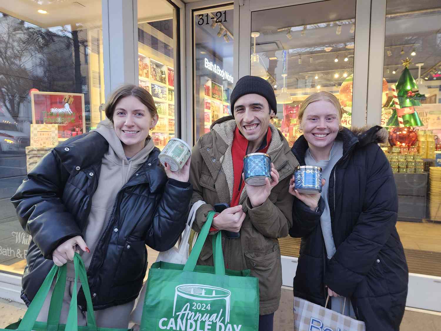 Brian Malheiro is flanked by Olivia Tuomey, left, and Rachael Earley outside of Bath & Body Works on Friday. 