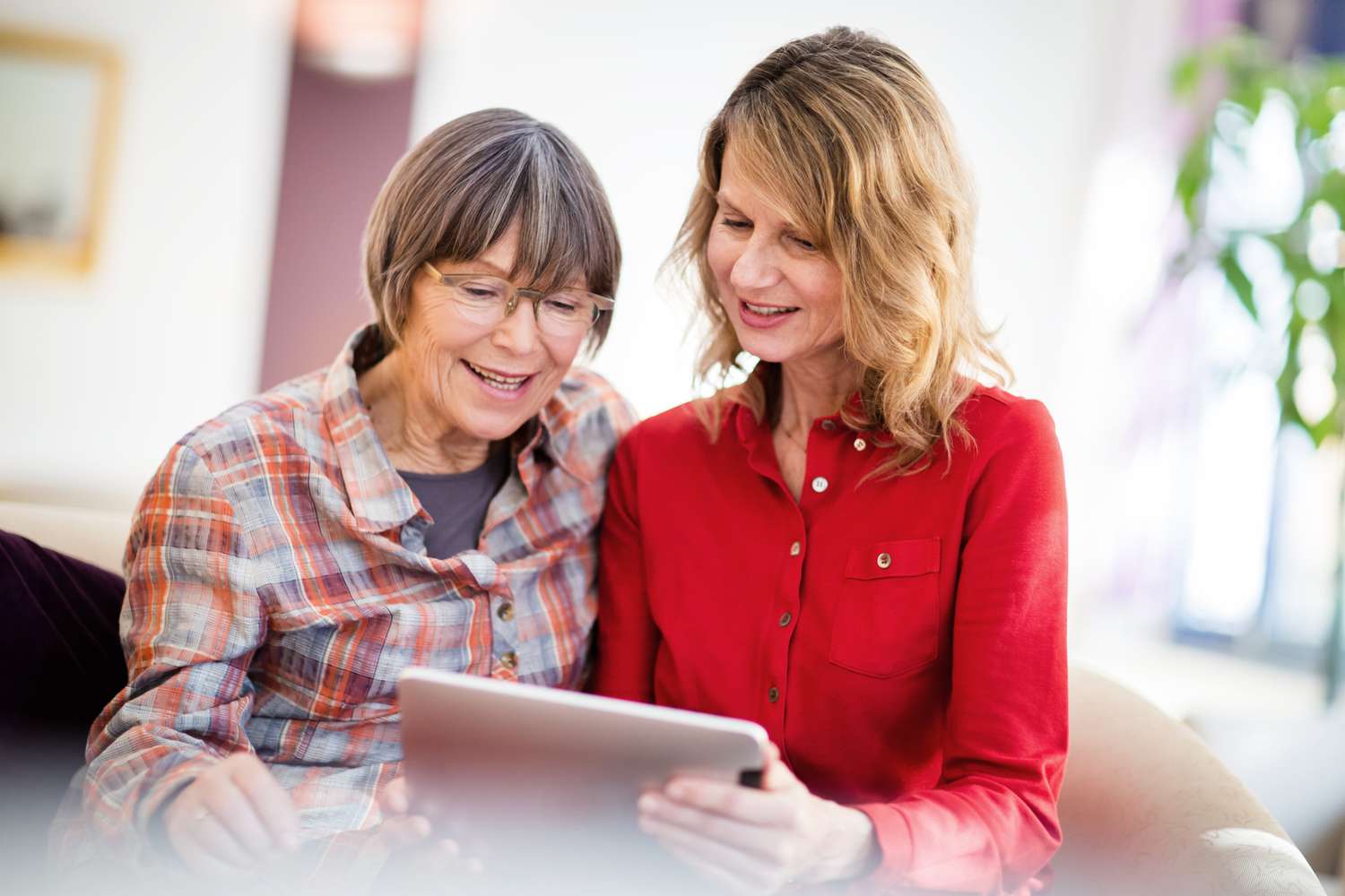 Two women talk while looking at a screen.