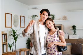 Young couple holding the keys to their newly purchased home in their living room