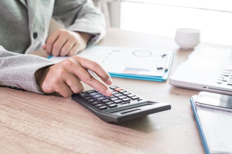 A businessman analyzing documents using his calculator.