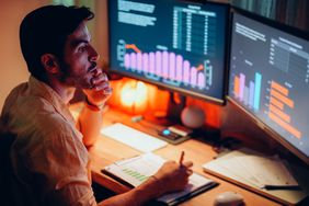 A person at a desk with two screens trading stocks overnight.