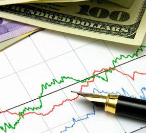 A pen and money on a stock chart. 