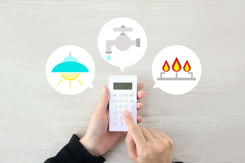 A person using a calculator surrounded by utilities services symbols