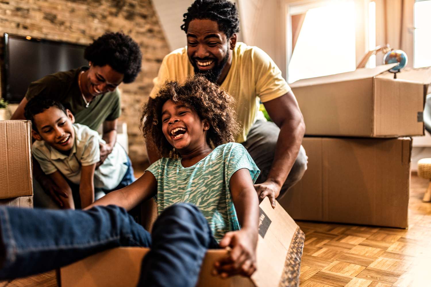 Family unpacking in a new home, children playing with empty boxes. 
