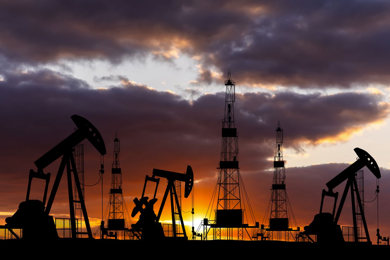Oil field with rigs at sunset. 