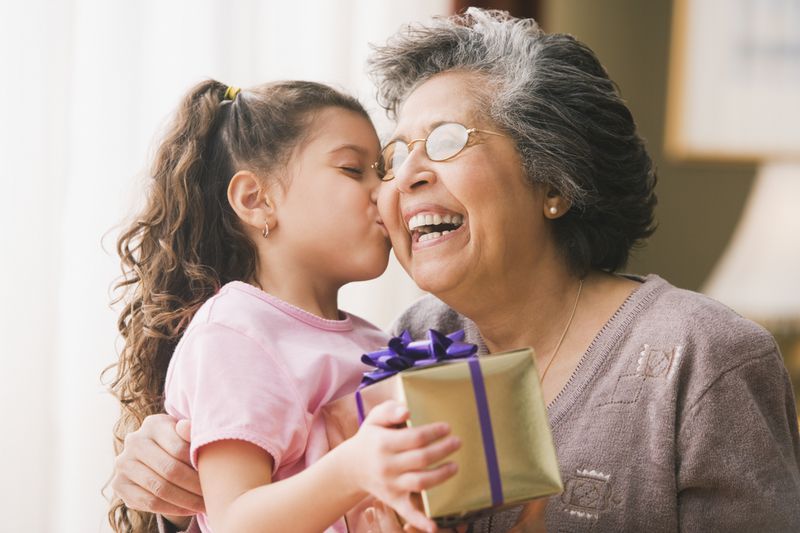 Granddaughter kissing grandmother and holding gift